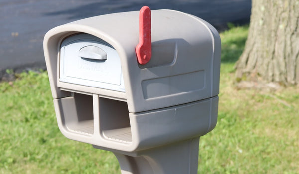 A gray plastic mailbox with the red flag up close up of the top